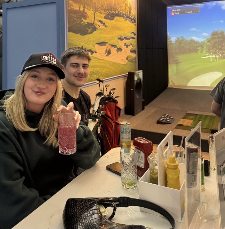 Friends with a drink at a table next to a simulator bay