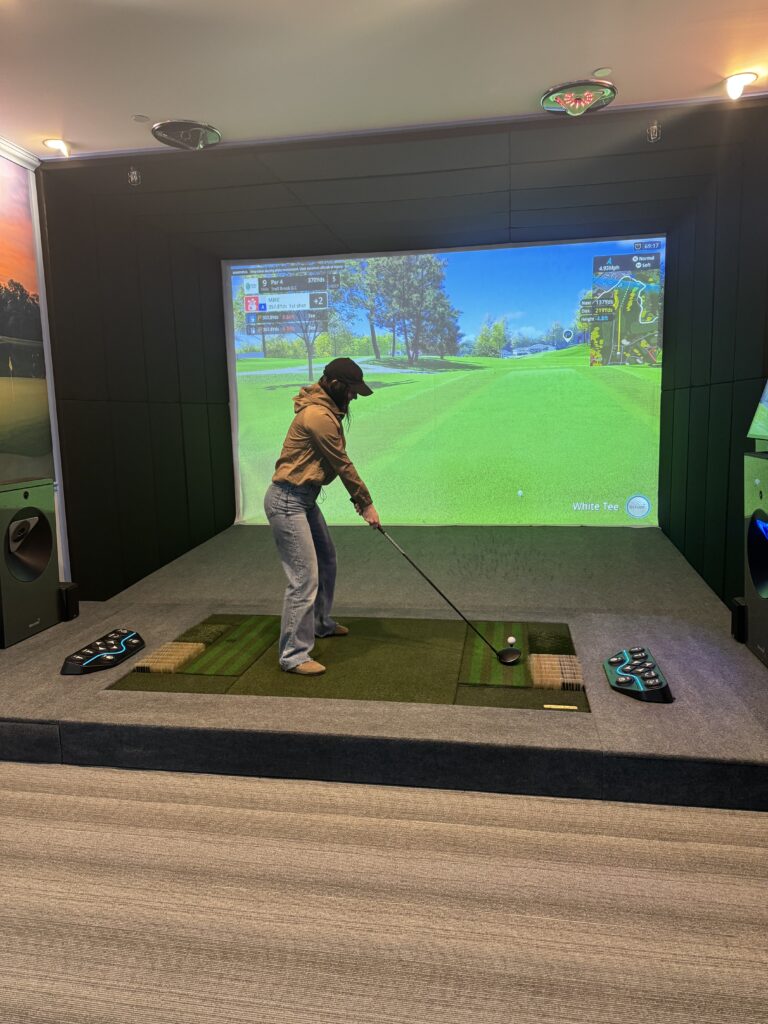 A golfer mid-swing on the hitting mat of a SimZon bay