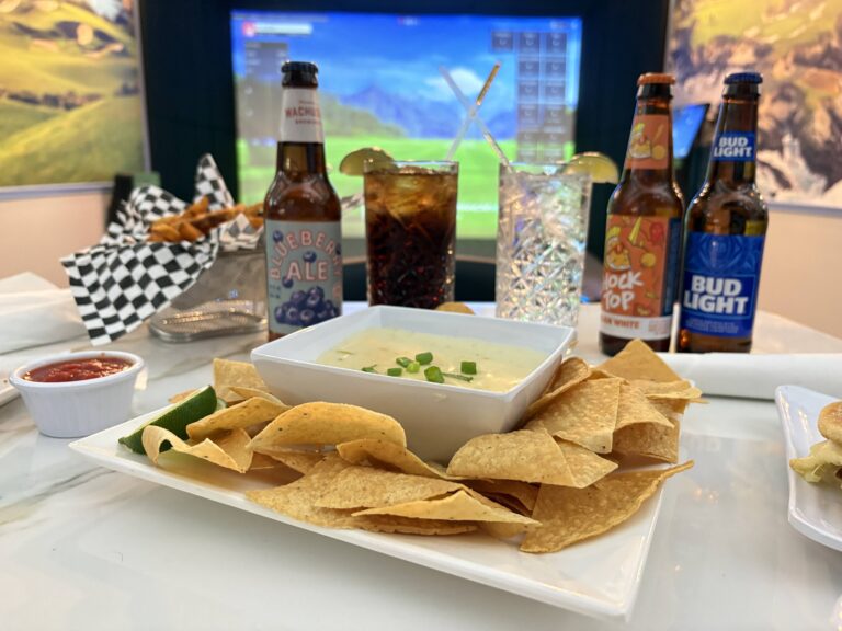 Queso and chips with drinks in front of the bays